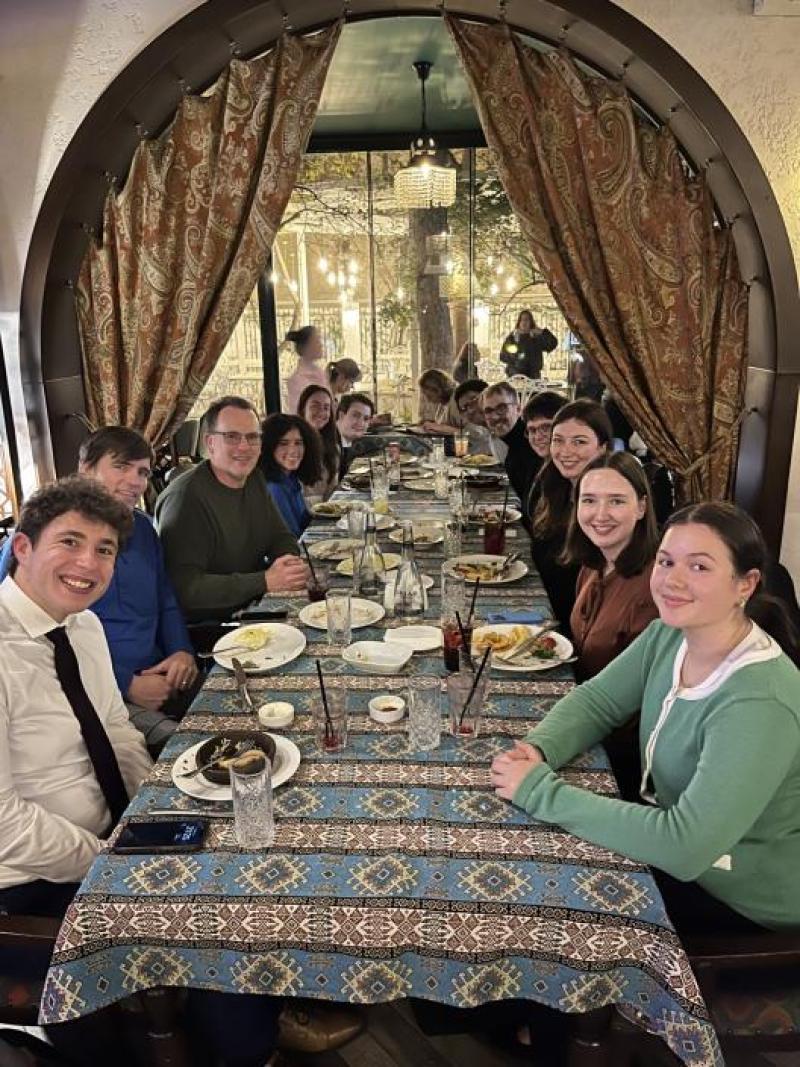 Students and professors sitting at a long table enjoying dinner