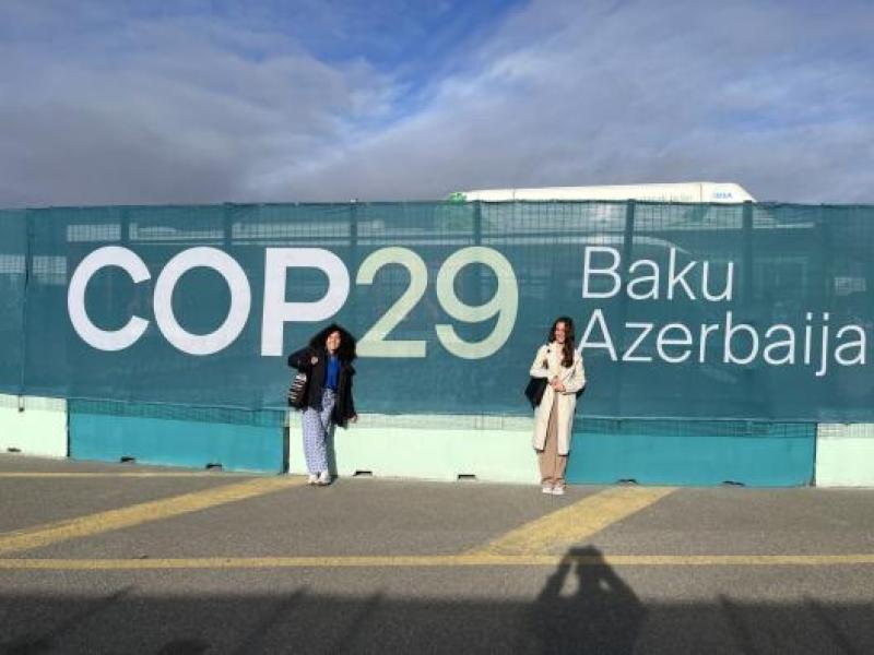 Students in front of a COP29 sign