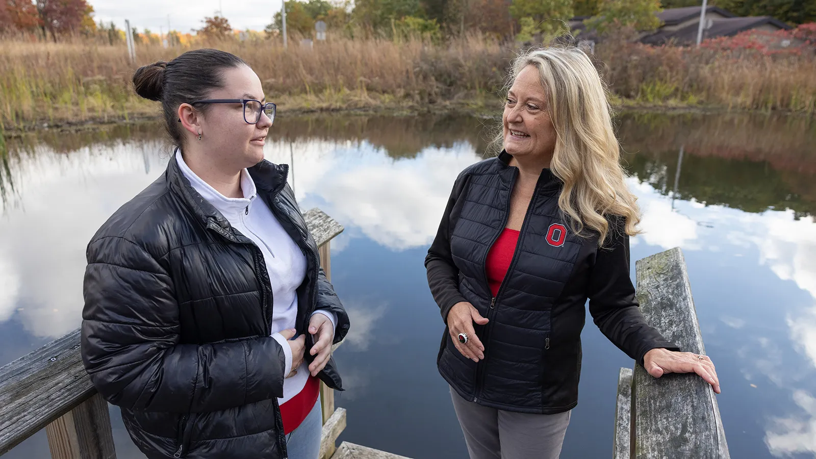 Student and professor stand on a wetlands boardwalk