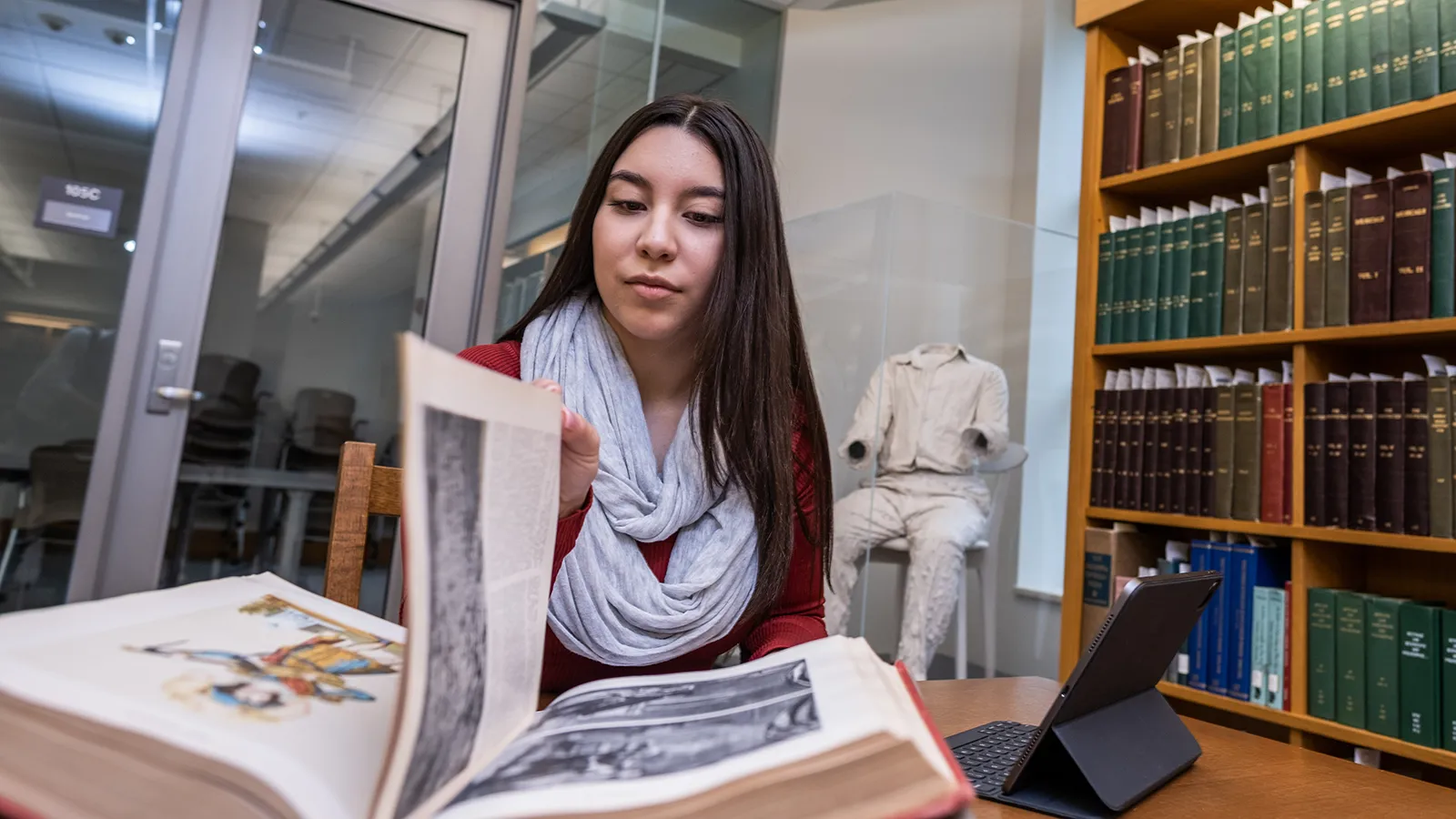 Student seated at a table looking through a book