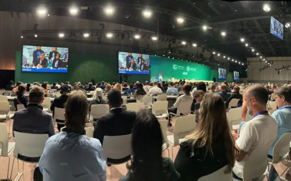 Audience members watching a presentation in a large auditorium at COP28