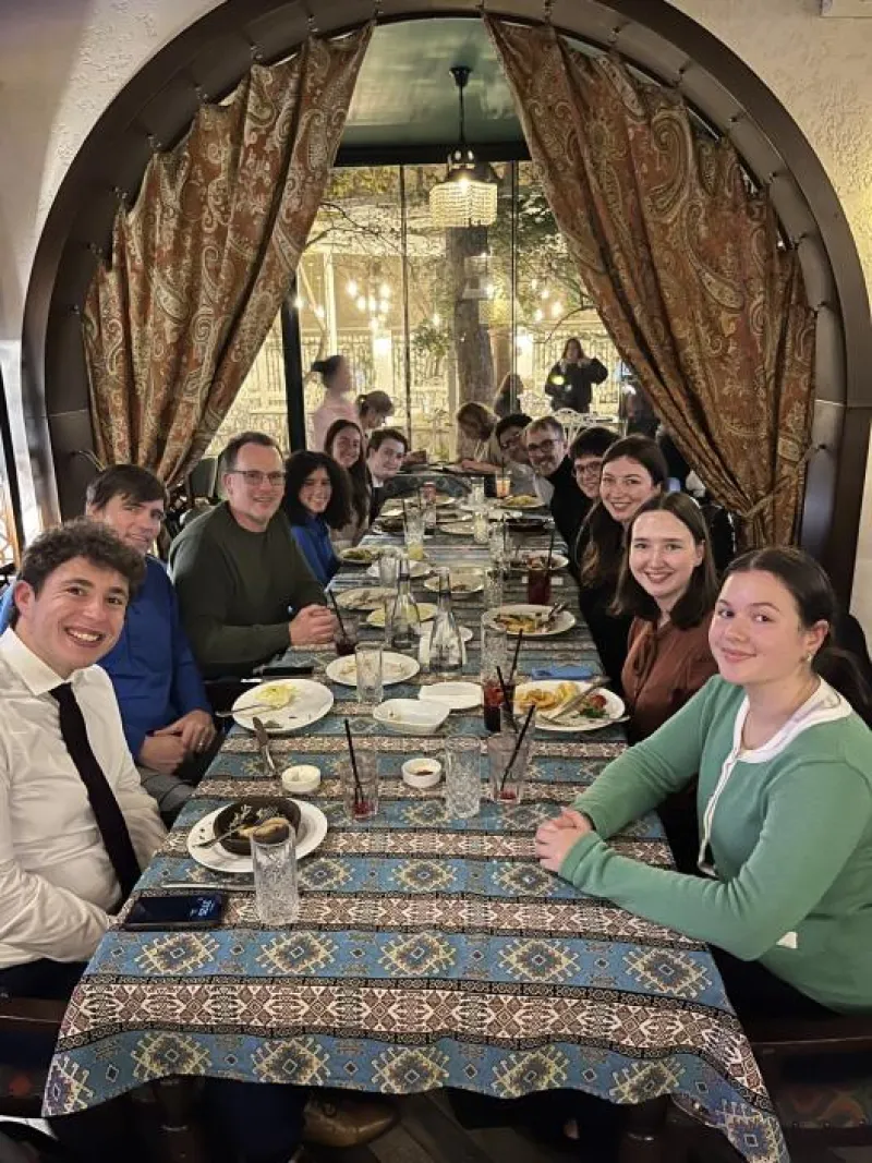 Students and professors sitting at a long table enjoying dinner