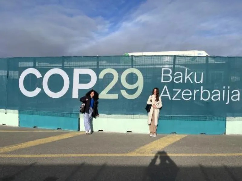 Students in front of a COP29 sign