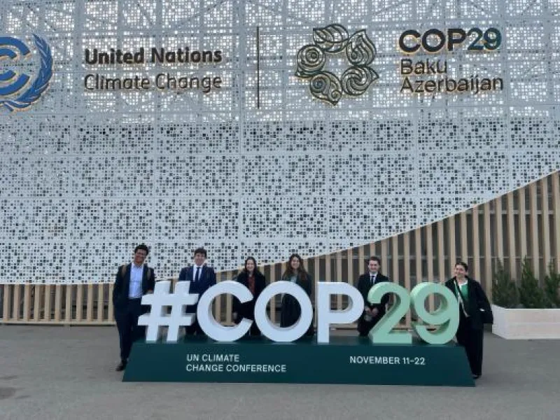 Students behind a sign that reads #COP29
