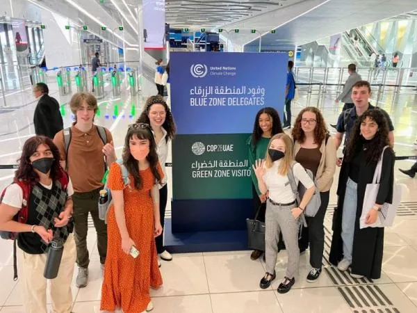Ohio State students standing in front of a COP28 sign in the United Arab Emirates